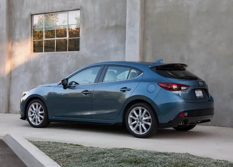 A backview of a blue Mazda parked