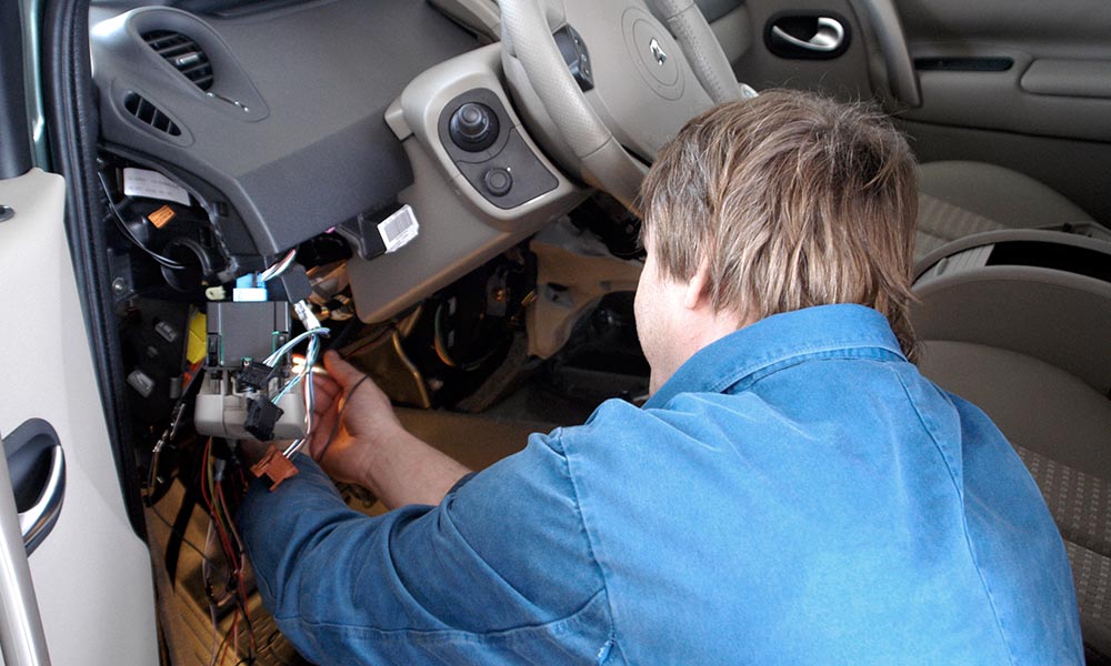 A backview of a person installing a car alarm system inside a car