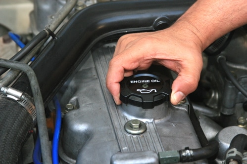 A person fastening a car's engine oil box cap