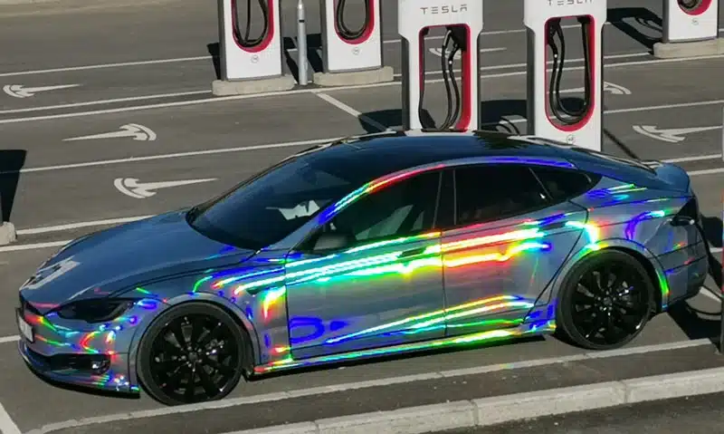 A side view of a car with holographic chrome wrap parked at a gas station