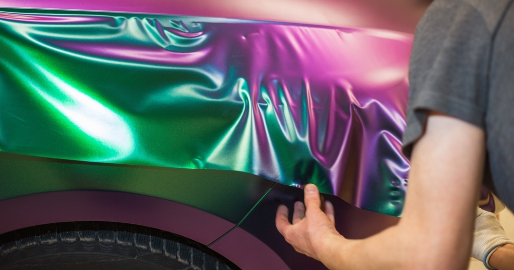 A view of a car being wrapped in foil purple color