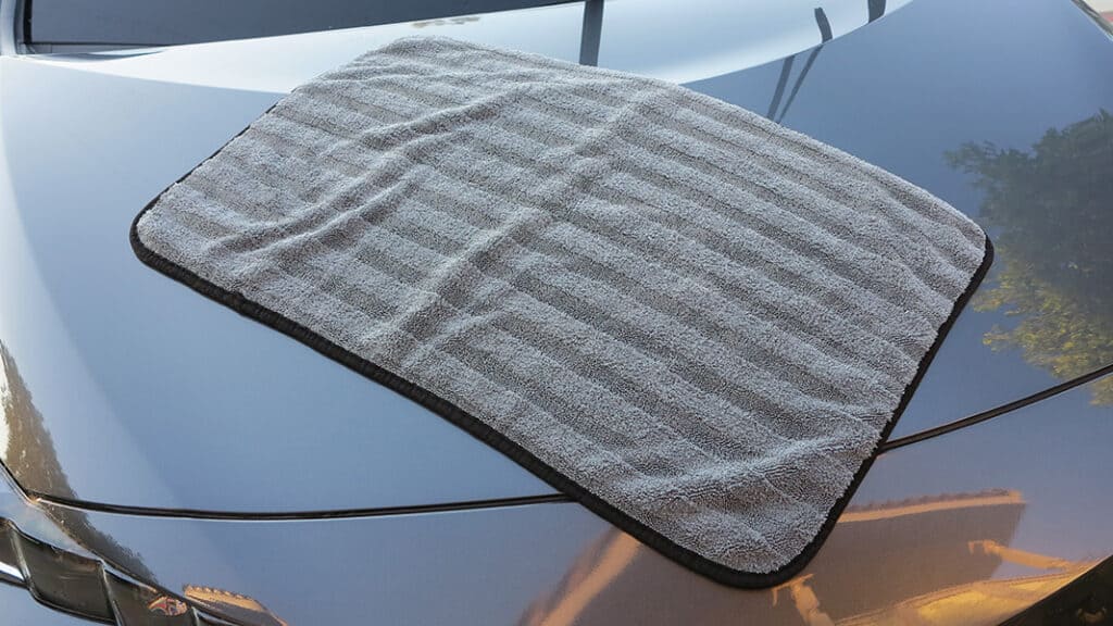 A view of a grey towel placed on a silver grey car bonnet