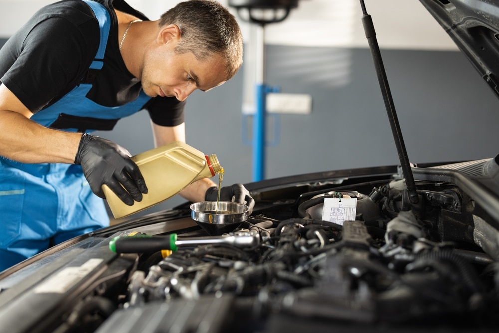 A view of a person adding oil into the car engine