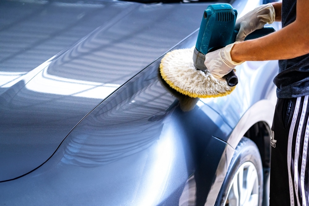 A view of a person applying car polish on a silver shiny car