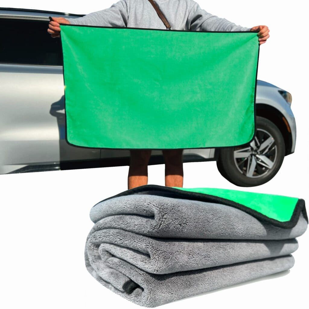 A view of a person holding a green and grey car towel standing in front of silver car