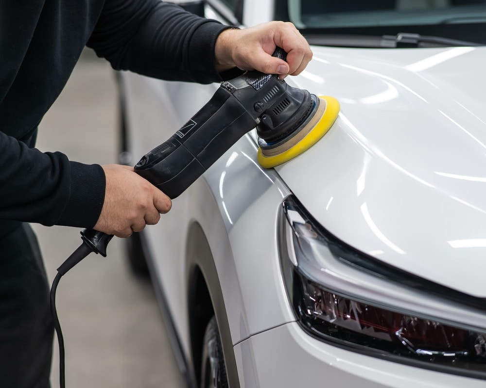 A view of a person polishing a white shiny car