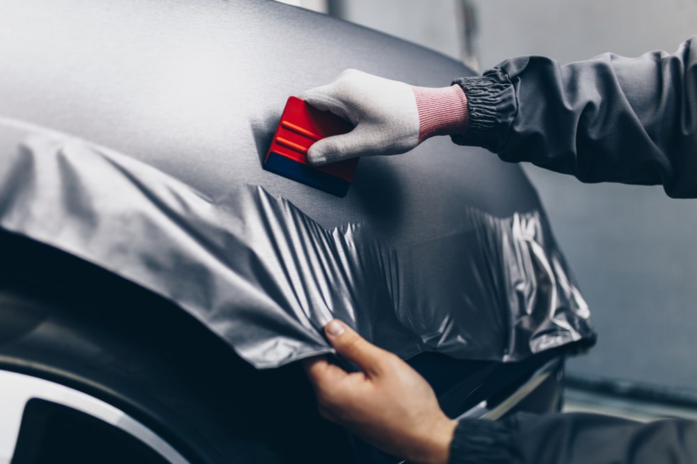 A view of a person putting vinyl foil on a car