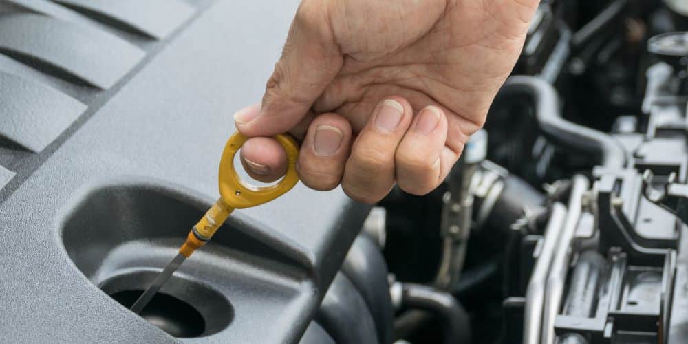 A view of of a person holding a dipstick to check oil in a car