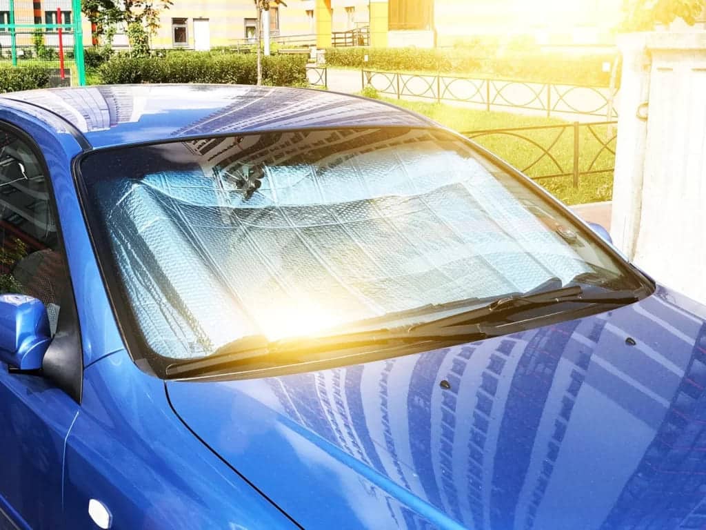a blue color parked car with sunshades on the windscreen