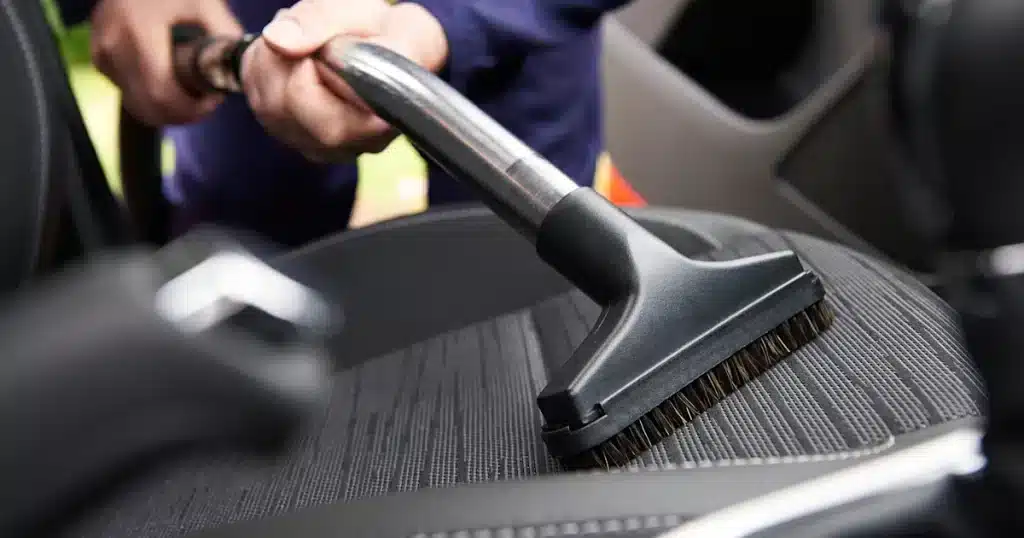 A person cleaning the car seat with a brush