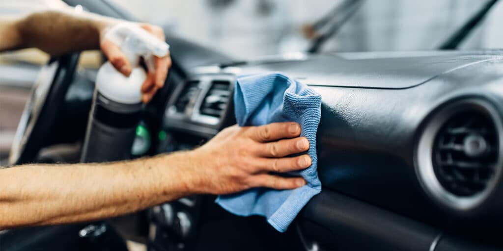 A person using a soapy cleaner to clean interior of a car