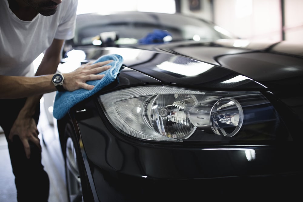 A view of a person cleaning a black car with a towel