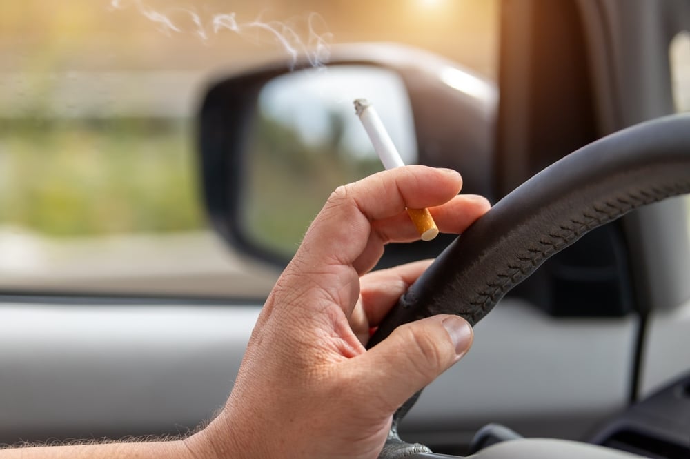 A view of a person holding a smoke driving car