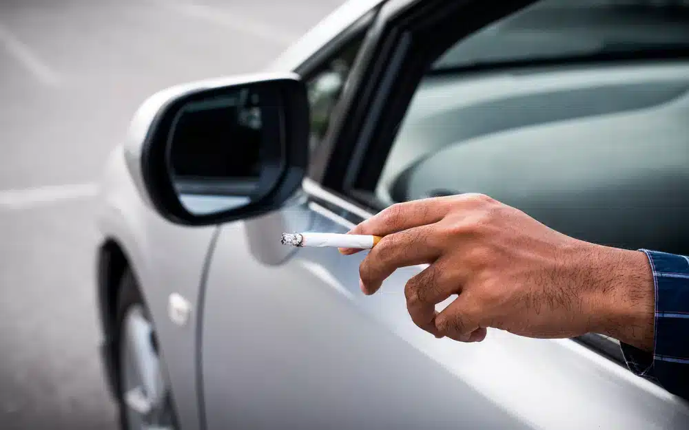 A view of a person holding cigarette butt out of the car