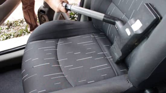 A view of a person vacuuming the car interior seats