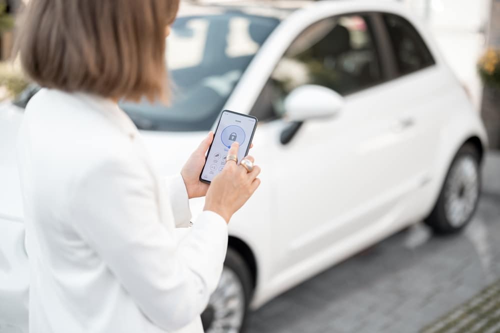 A view of a woman turning on a car alarm with a phone