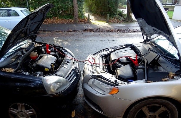 a dead car and good battery car connected with jumper cables to jumpstart