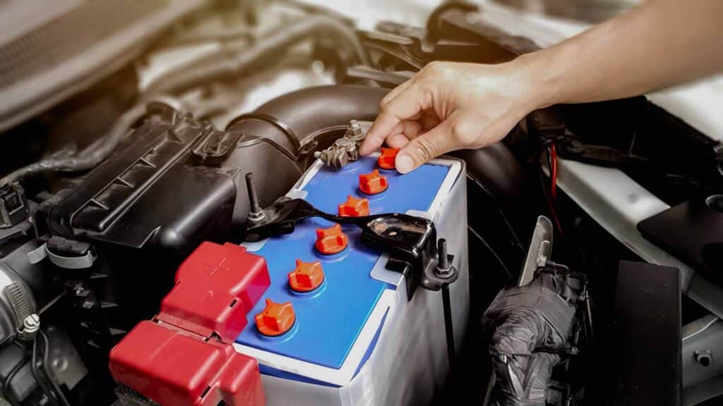 a man checking the terminals of a car battery