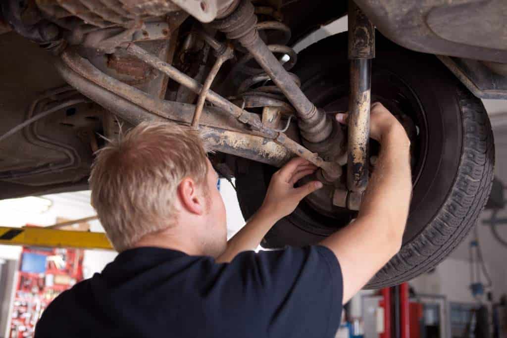 A backview of a mechanic fixing a car's axles