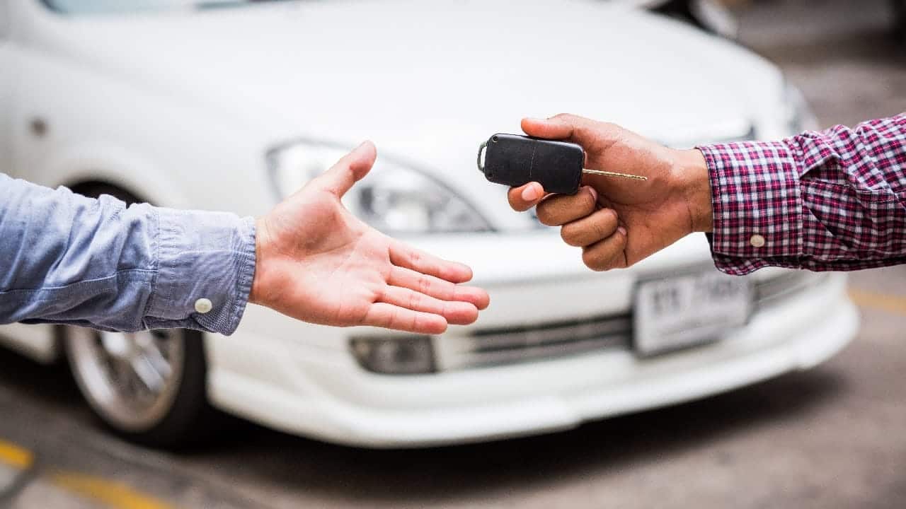 A view of a guy handing a car key to another guy