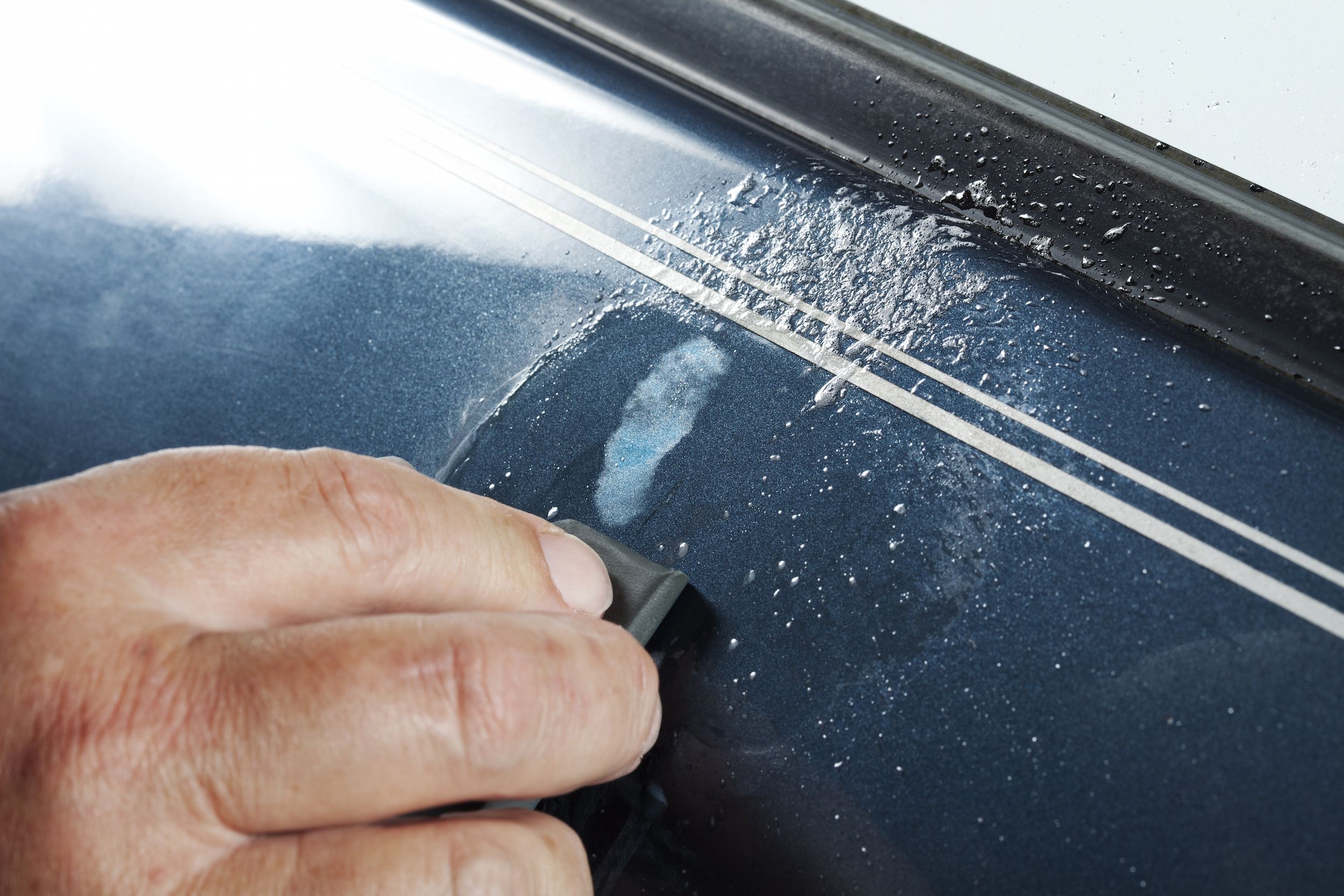 A view of a person removing scratches from a blue car