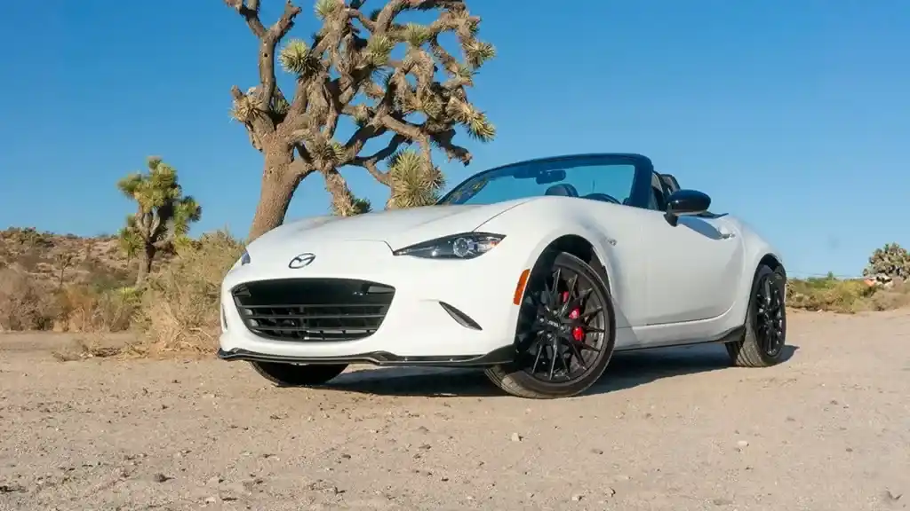 A view of a white mazda miata standing in a deserted place