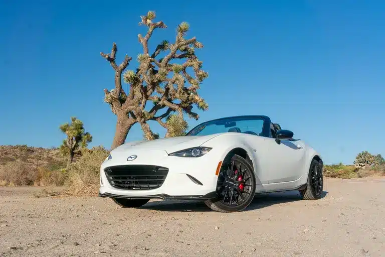 A view of a white mazda mx miata sports cars parked in a desert