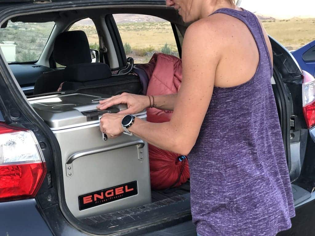 A view of a woman keeping a cooler inside the car back