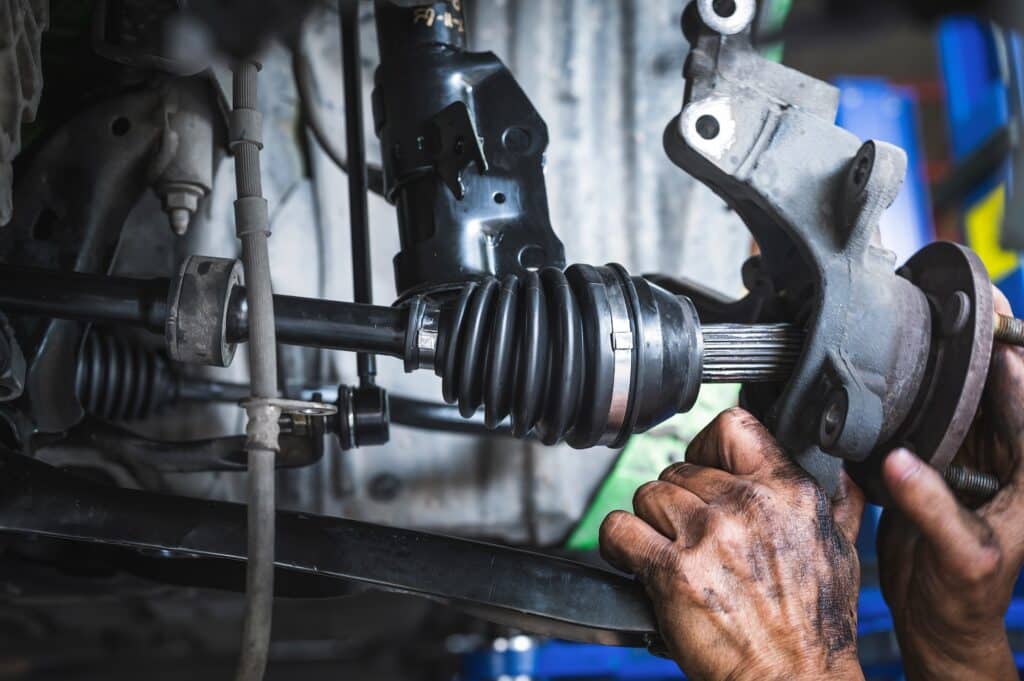 A view of mechanic's hands holding the car axles