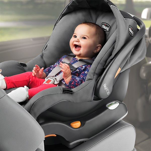 A view of a happy baby sitting inside a baby car seat