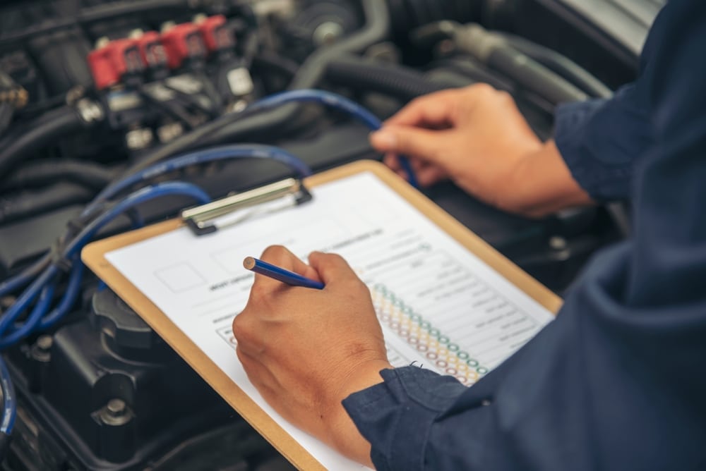 A view of a person checking the factors for car inspection placing the checklist on the car bonnet