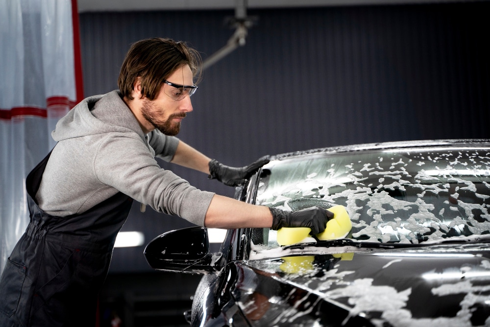 A view of a person scrubbing a car with soapy sponge