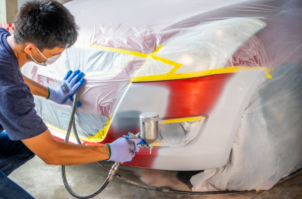 A view of a person spraying primer color on a car