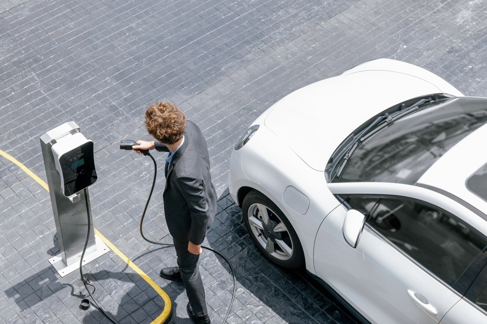 An aerial view of a man charging a hybrid car