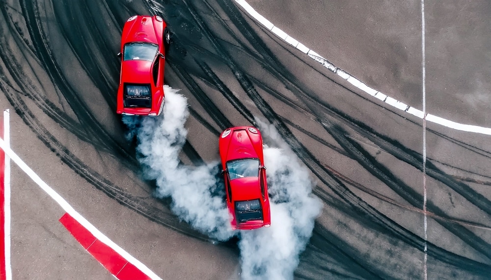 An overhead view of a two red cars drifting